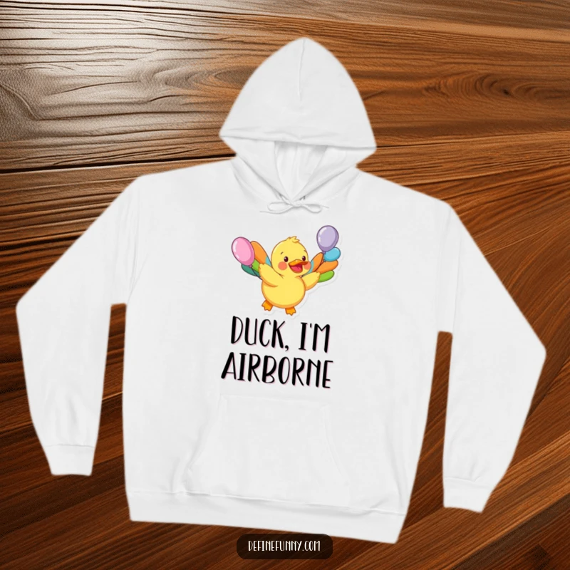 Funny hoodie depicting a happy rubber duck character with mismatched balloon wings attempting flight, perfect for cozy whimsical humor.